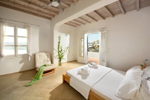Une chambre avec un lit, une chaise, une plante en pot et une vue sur une colline.