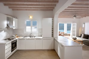 Une cuisine moderne avec des armoires blanches, un four encastré et une grande fenêtre donnant sur un paysage magnifique.
