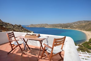 A terrace with a table and chairs overlooking a coastal landscape. - Villa 'Wonderful Chrysta' with Sea View and Pool (Mykonos)