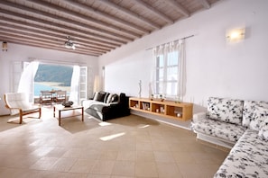 Ein Wohnzimmer mit einer Couch, einem Sessel, einem Couchtisch, einer Holzkonsole und Meerblick.