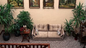 Een gezellige woonkamer met een beige bank, een klein houten tafeltje en diverse potplanten.