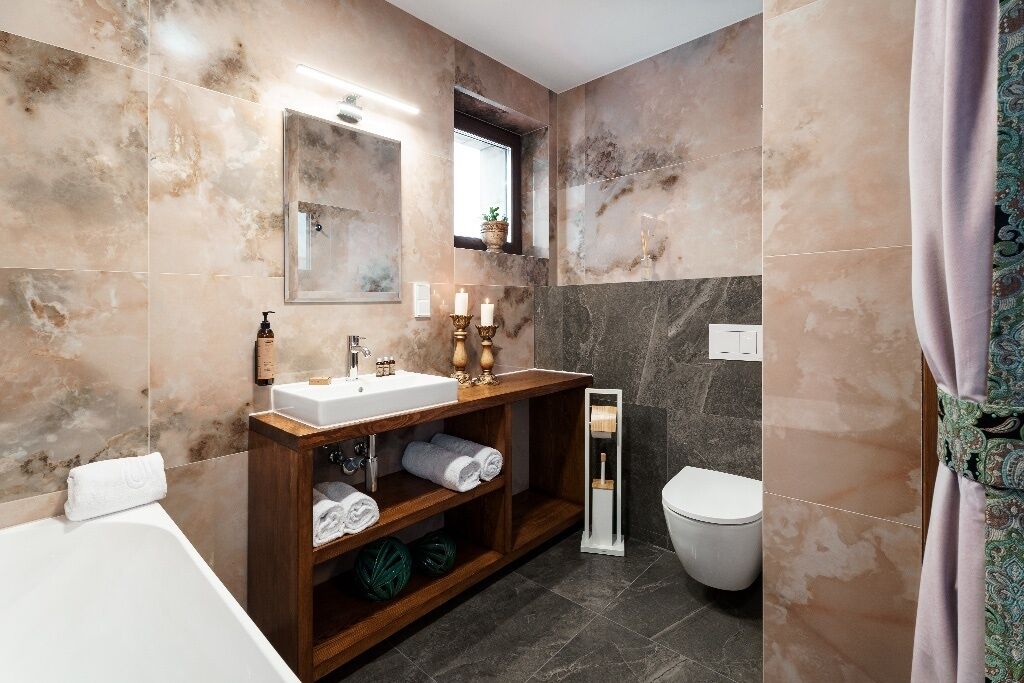 A modern bathroom with a marble vanity, a toilet, and a shower area.