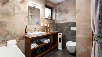 A modern bathroom with a marble vanity, a toilet, and a shower area.