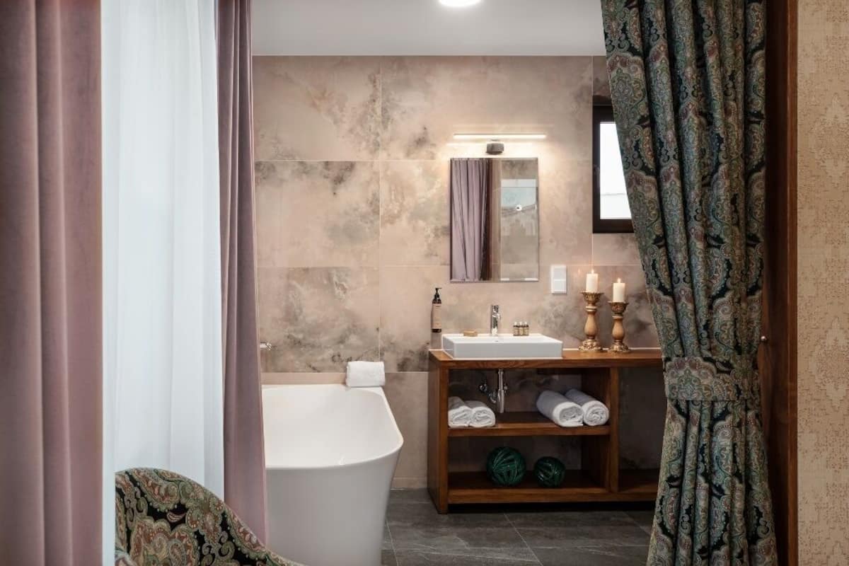A modern bathroom with a freestanding bathtub, a vanity with a mirror, and a shelf with towels.