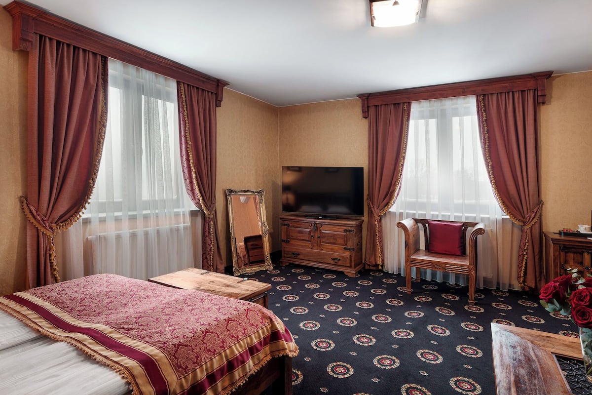 A hotel room with a large bed, a wooden dresser, a television, and a chair.