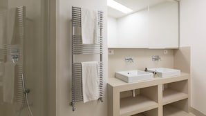 A modern bathroom with a glass shower enclosure, a towel rack with two towels, a white sink vanity, and a large mirror. - Casa Luce, a Burghesius home (Roma)