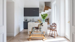 A modern kitchen with a marble island, a wooden rocking horse, and a dining area with a wooden chair. - Casa Luce, a Burghesius home (Roma)
