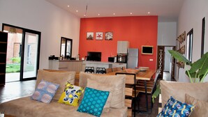 En moderne stue med sofa, spisebord og et køkkenområde med en rød accentvæg.
