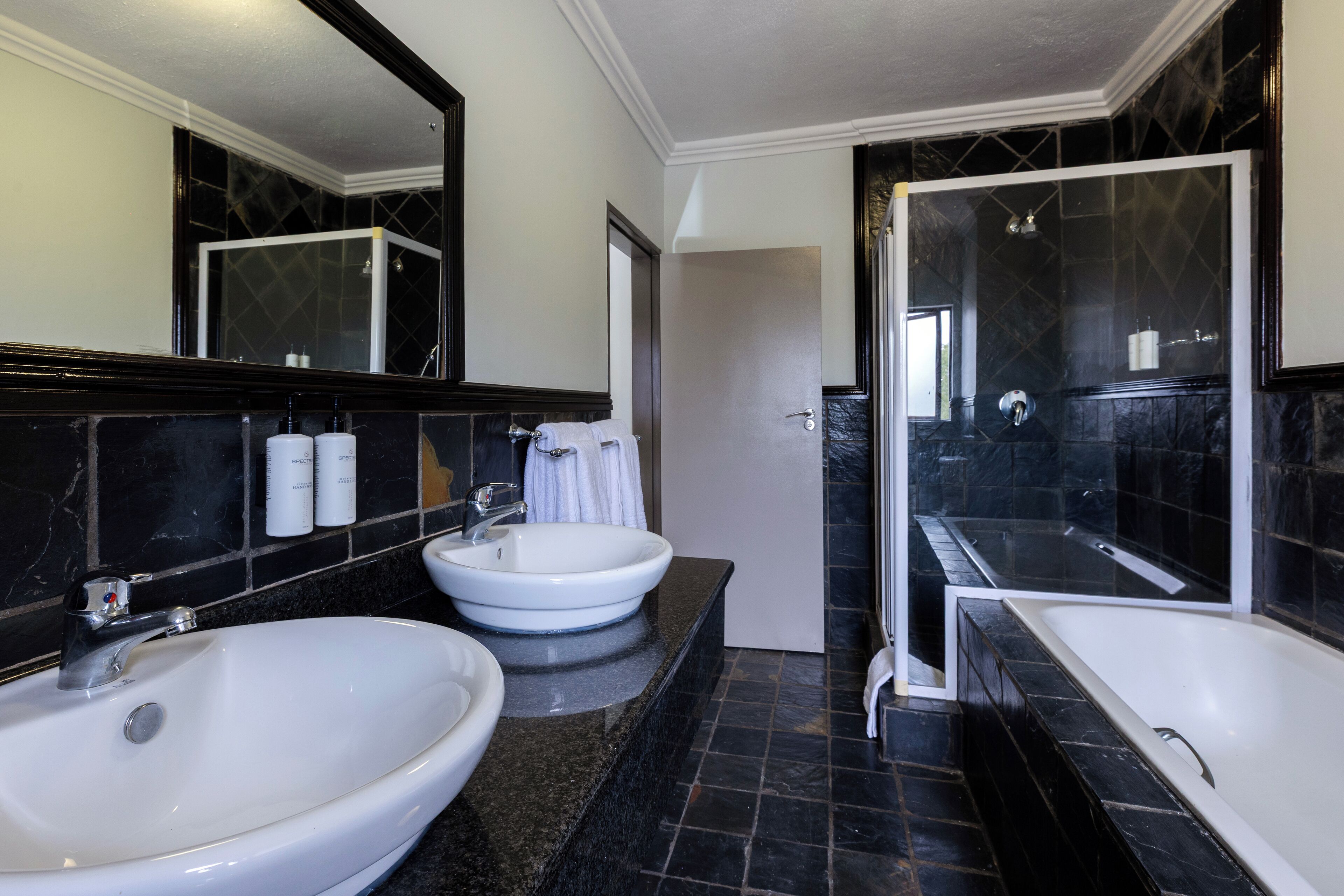 A bathroom with two sinks, a bathtub, and a shower.