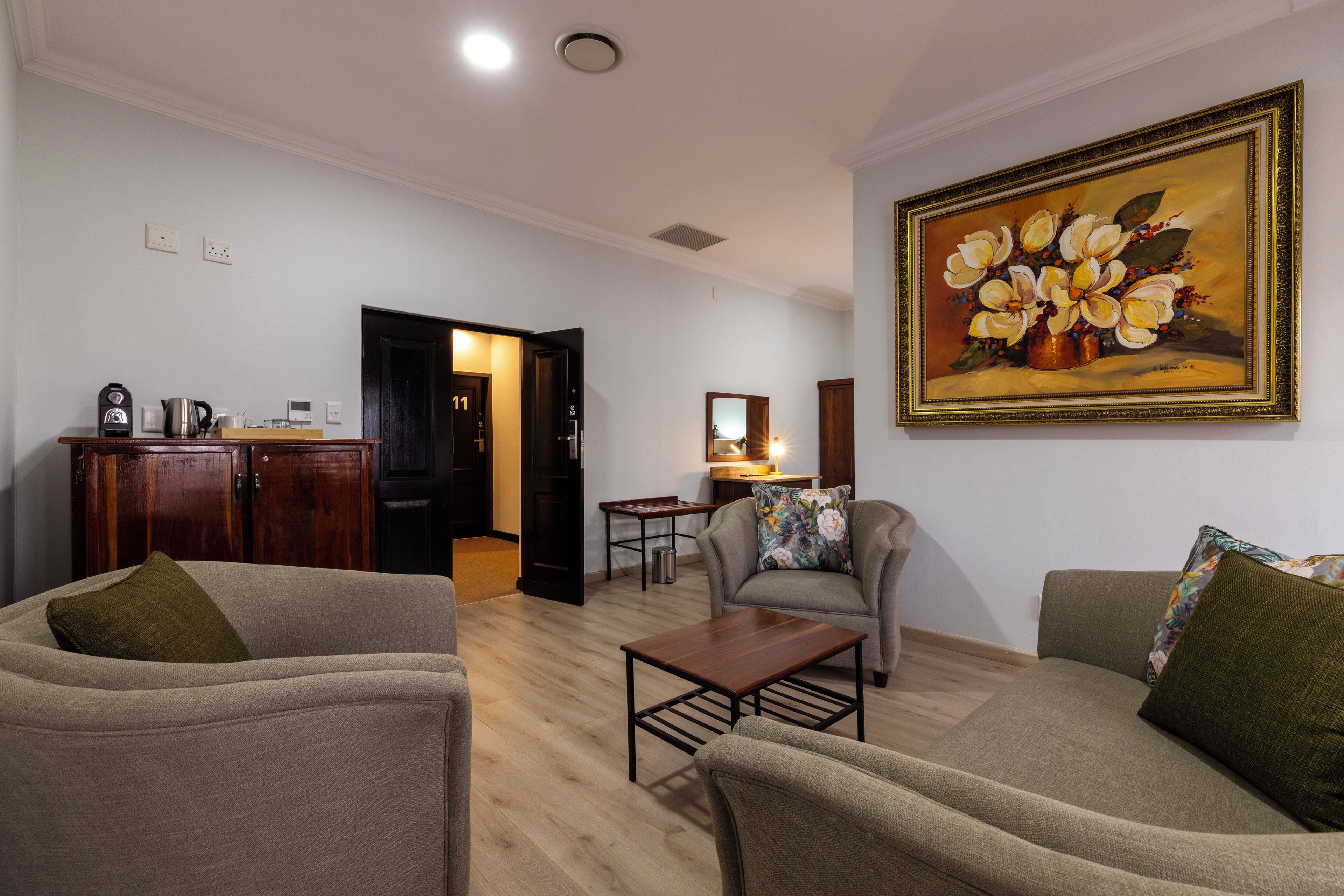 Una sala de estar con sofá, sillón, mesa de centro y un cuadro en la pared.
