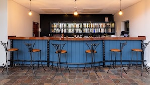 A bar with a wooden counter, black metal stools, and a blue wall. - Basdenwood Hotel  (Centurion)