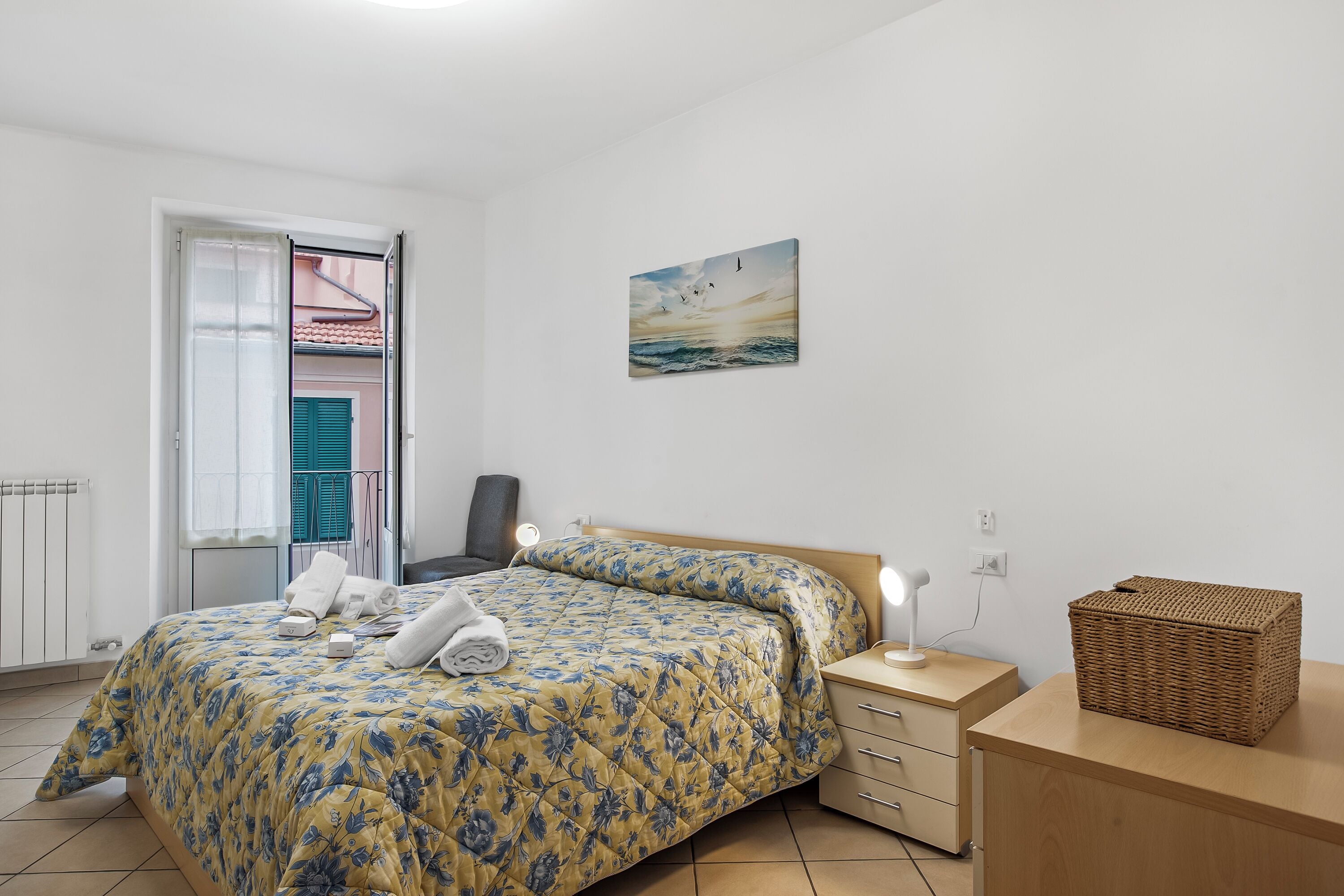 A bedroom with a bed, bedside table, lamp, and a painting on the wall.