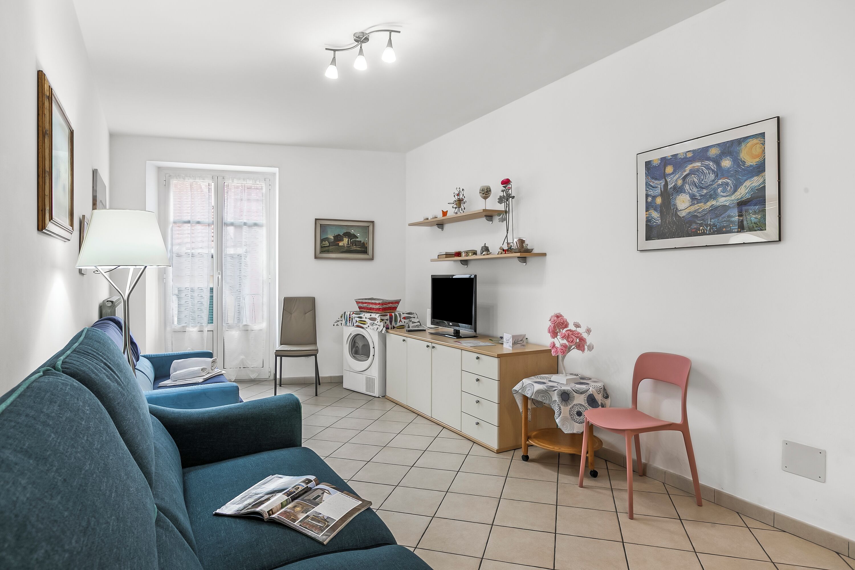 Una sala de estar con sofá, una mesa y una silla, lavadora y televisor.
