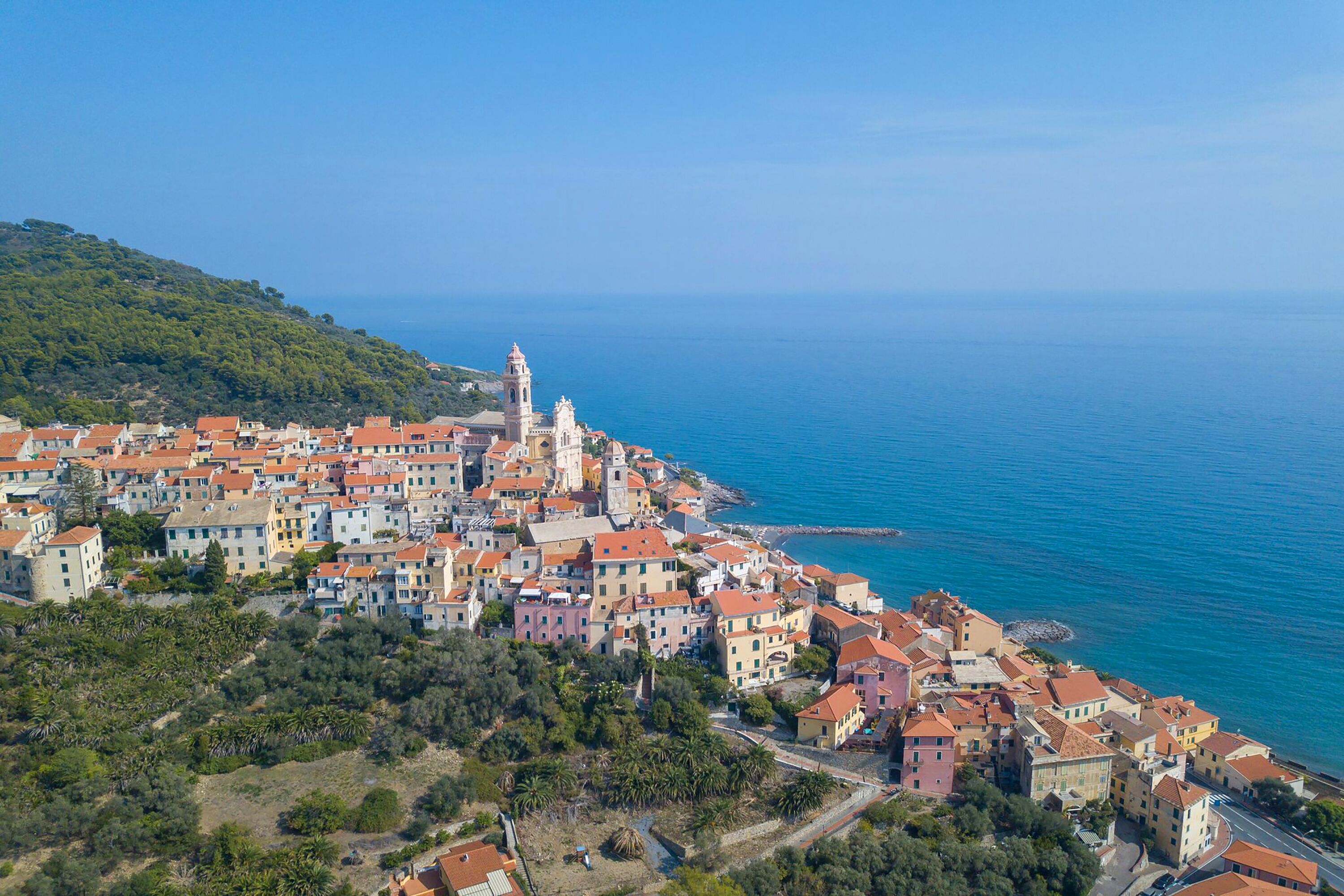 A coastal town with buildings along the sea, a prominent church, and a rocky shoreline.