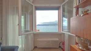 Una habitación con un ventanal grande, un radiador, un armario de madera y una silla.