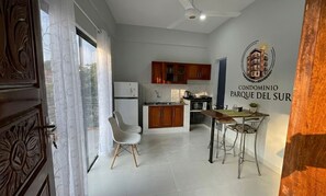 Una cocina moderna con armarios de madera, un refrigerador y una zona de comedor con mesa y sillas.