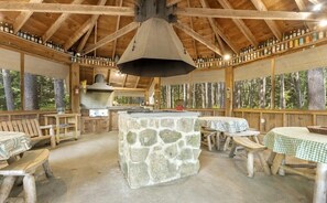 A rustic wooden cabin with stone flooring, wooden benches, and tables.