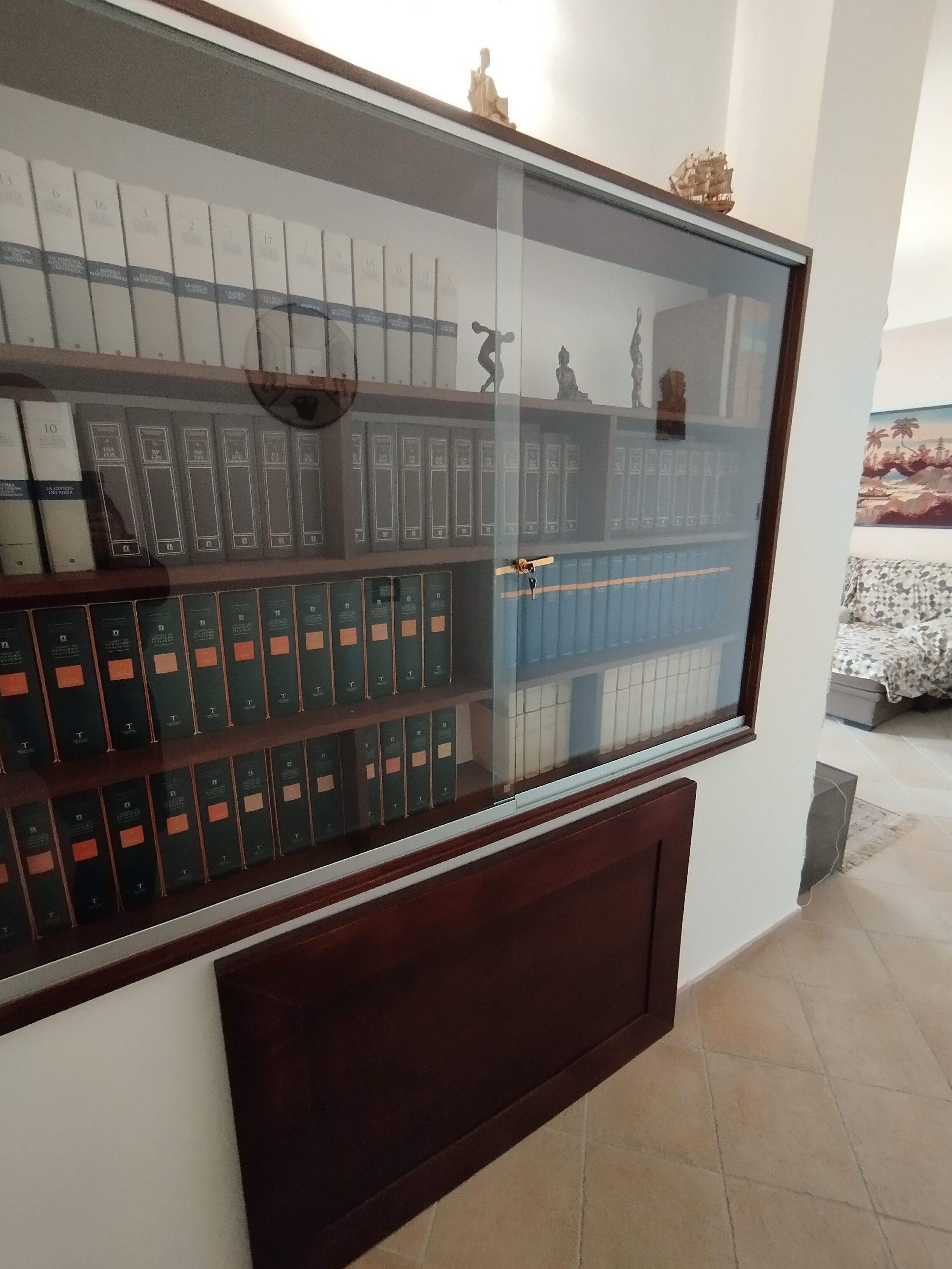Une vitrine contenant des ouvrages de droit et une statue.
