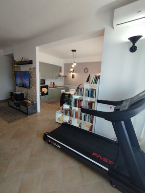 Un salon moderne équipé d’un tapis de course, d’une bibliothèque et d’un téléviseur.