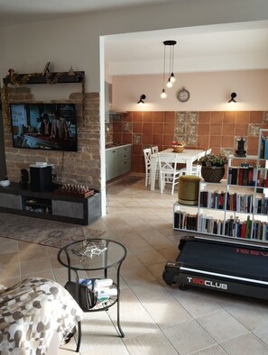 Un salon moderne équipé d’un téléviseur, d’une bibliothèque et d’appareils de musculation.