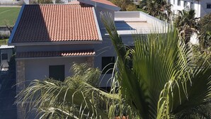 A building with a red-tiled roof, surrounded by palm trees and a clear view of the sea. - B&B panoramico, situato a 250 metri dalla spiaggia (Praia a Mare)