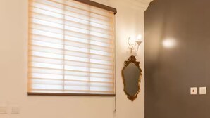 Une pièce avec une grande fenêtre, un miroir et un interrupteur sur le mur.