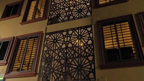Une façade d’immeuble avec de nombreuses fenêtres, dont certaines sont ornées de motifs décoratifs en treillis.