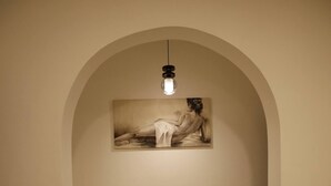 Un couloir doté d’un sol carrelé, d’une porte en arc de cercle et d’un tableau accroché au mur.