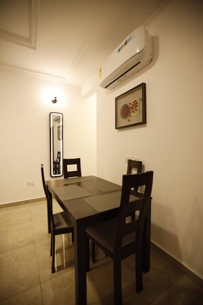 A dining area with a table, chairs, an air conditioning unit, a framed artwork, and a mirror. - Apartment in Botwe (Ashaley Botwe)