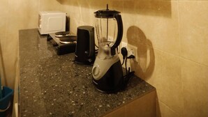 Une cuisine équipée d’un plan de travail, d’un mixeur, d’un grille-pain et d’un placard.