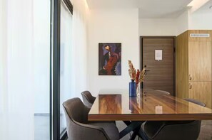 A modern dining area with a glass table, chairs, a vase with dried flowers, and a painting on the wall. - 131 LIM 101 - Stay Anna Residence City View Apa (Limassol)