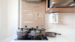 Une cuisine équipée d’une cuisinière à gaz, de casseroles, d’une poêle, d’un four à micro-ondes et d’un four encastré dans le mur.