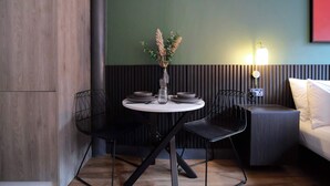 A dining area with a round table, black chairs, a vase with dried flowers, and a wall-mounted light fixture. - Stay Awhile - Boutique Studio Northern Quarter (Manchester)