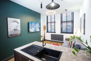 Een moderne keuken met een zwarte spoelbak, een marmeren aanrechtblad en een stadslandschap schilderij aan de muur.