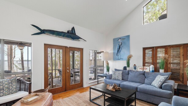 Un salon spacieux avec une grande fenêtre, une table à manger en bois, un canapé bleu et une sculpture de poisson fixée au mur.