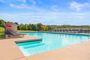 A swimming pool with lounge chairs and umbrellas, surrounded by a fence and trees. - The Lakeview Condo Lakefront (Branson)