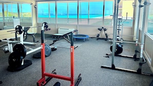 A gym with various exercise equipment, large windows, and a view of the beach. - Lovely 1 bedroom beach front studio, amazing beach access and location in PCB (Panama City Beach)