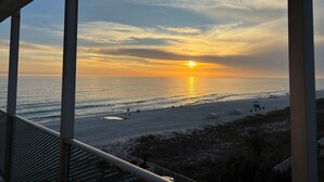 A sunset view from a balcony overlooking a beach with a clear sky. - Lovely 1 bedroom beach front studio, amazing beach access and location in PCB (Panama City Beach)