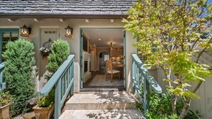 Une maison avec un escalier menant à une salle à manger, entourée de plantes en pot et d’un arbre.