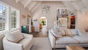 Un vaste salon doté d’un haut plafond, d’un escalier et d’une vue sur la cuisine.