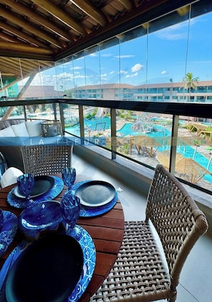 Espaço de refeições com vista para uma piscina e edifícios do resort.
