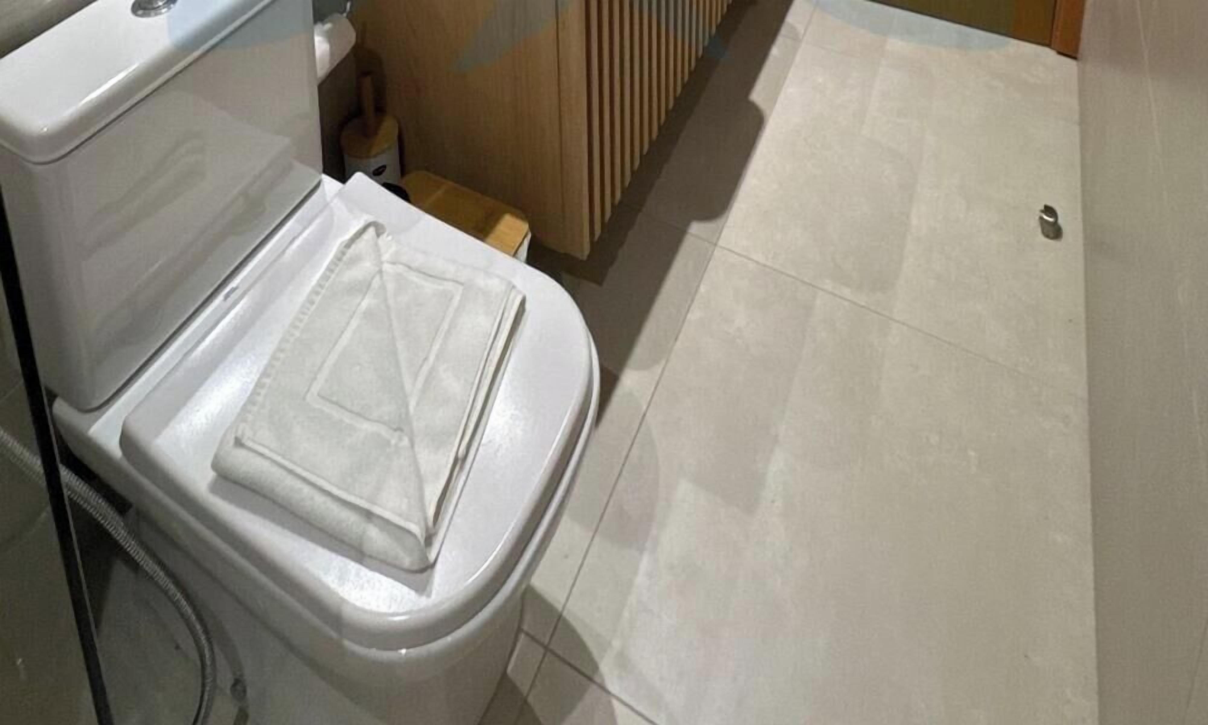 A white toilet with a closed lid, a wooden cabinet, and a tiled floor.