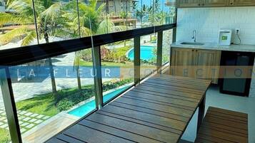 Cozinha moderna com armários de madeira e uma janela ampla com vista para uma área de piscina.
