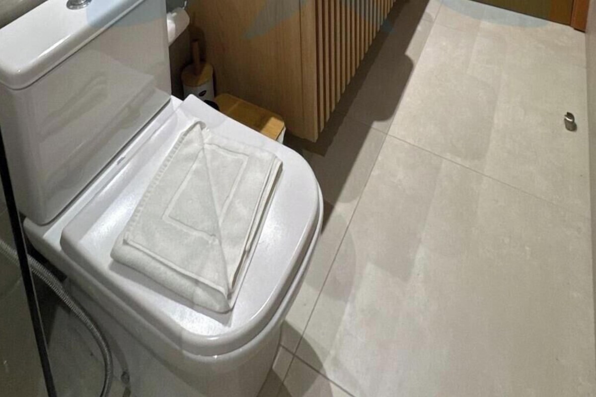 Un inodoro blanco con la tapa cerrada, piso de madera y pared con azulejos.