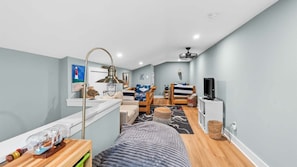 Un espacio habitable compacto con kitchenette, cama, televisor y un pequeño comedor.