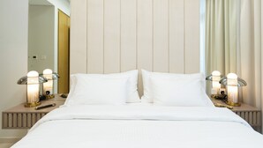 A neatly made bed with white linens, two bedside lamps with clear shades, and a wooden nightstand with a remote control. - Luxury 2BR Skyline Retreat - Aykon City (Dubai)