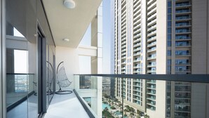 A modern apartment with a balcony overlooking a cityscape and a pool area. - Luxury 2BR Skyline Retreat - Aykon City (Dubai)
