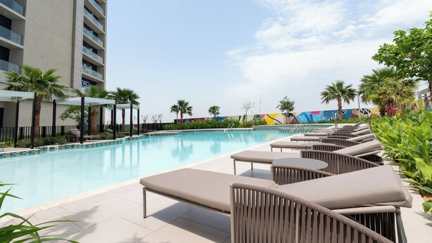 A poolside area with lounge chairs and a swimming pool. - Luxury 2BR Skyline Retreat - Aykon City (Dubai)