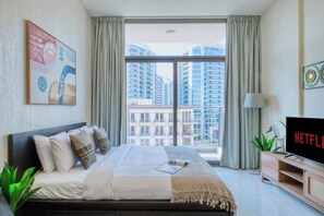 Ein modernes Hotelzimmer mit einem großen Bett, einem Fernseher und Blick auf hohe Gebäude.