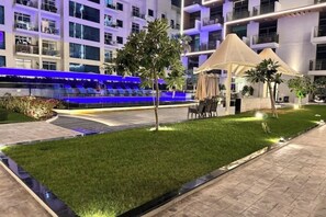 Ein moderner Hotelinnenhof mit Pool, Sitzgelegenheiten im Freien und einem gepflegten Rasen.